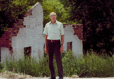 Ray Peterson Standing in Front of Peterson Home Ruins